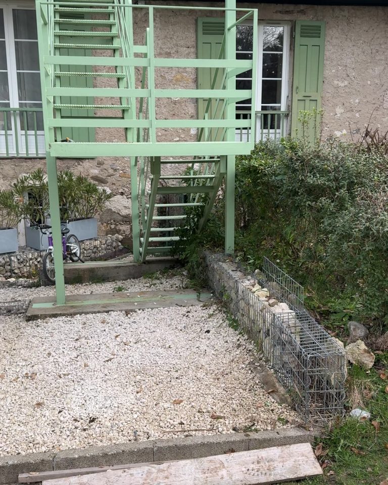 Cour en gravier au pied d’un escalier métallique à Sevrier, avant les travaux