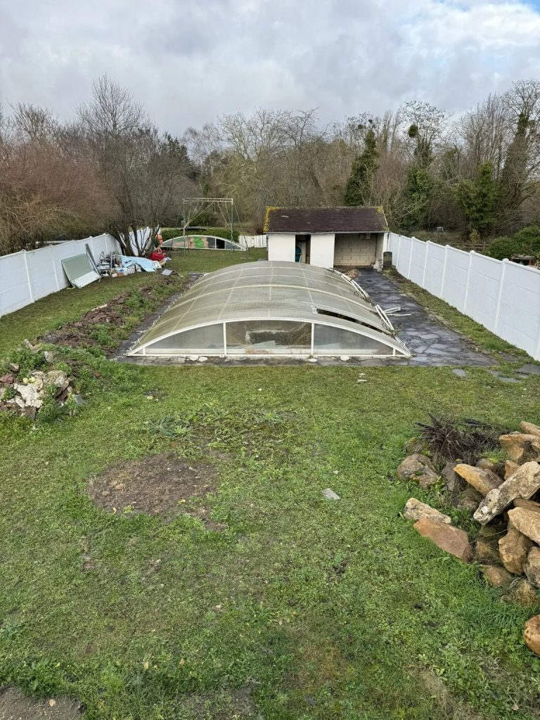 Le jardin avant le projet : piscine sous son abri, pelouse abîmée et tas de pierres