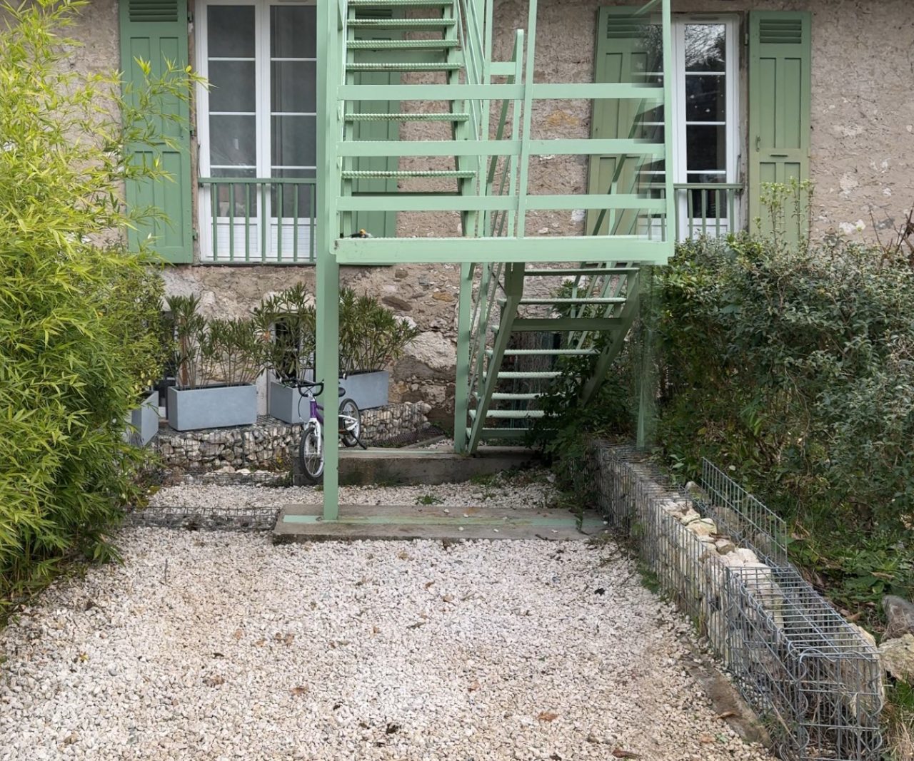 Sevrier (74), avant les travaux : une cour en gravier au pied de l’escalier, entre bambous et gabion