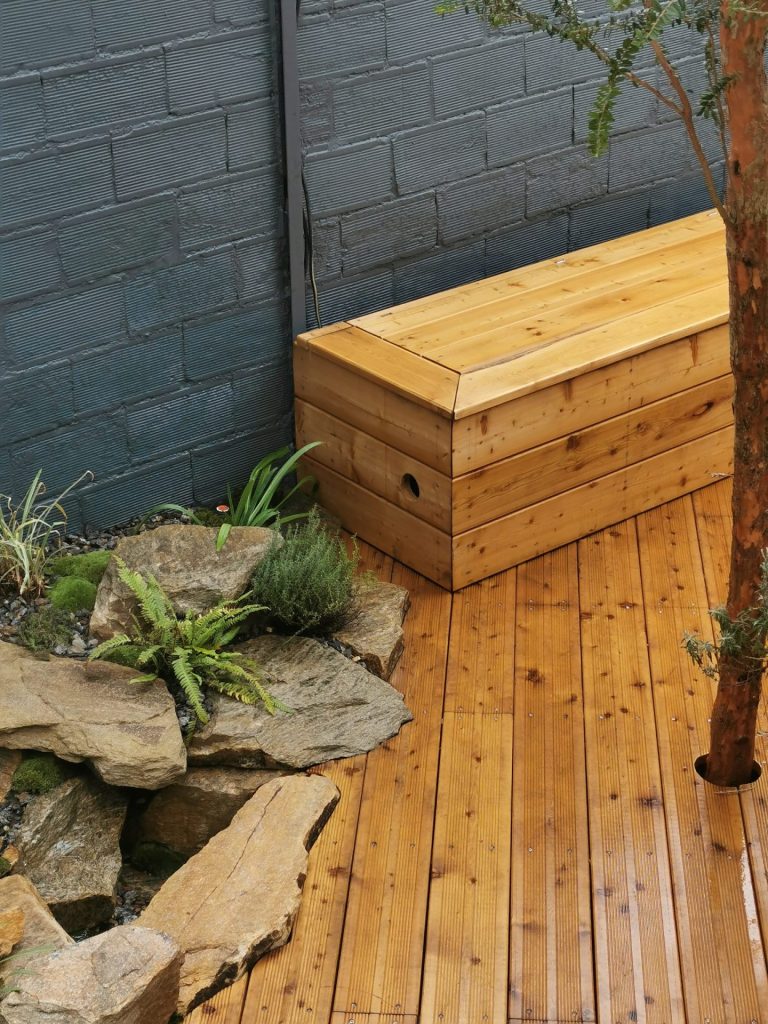 Banc en mélèze avec coffre dans un jardin de cour à Colombes (92)