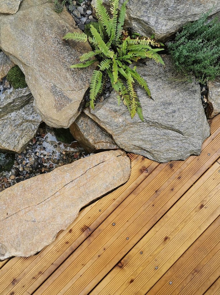Bois, pierres naturelles et végétation réunis au bord de la cascade à Colombes (92)