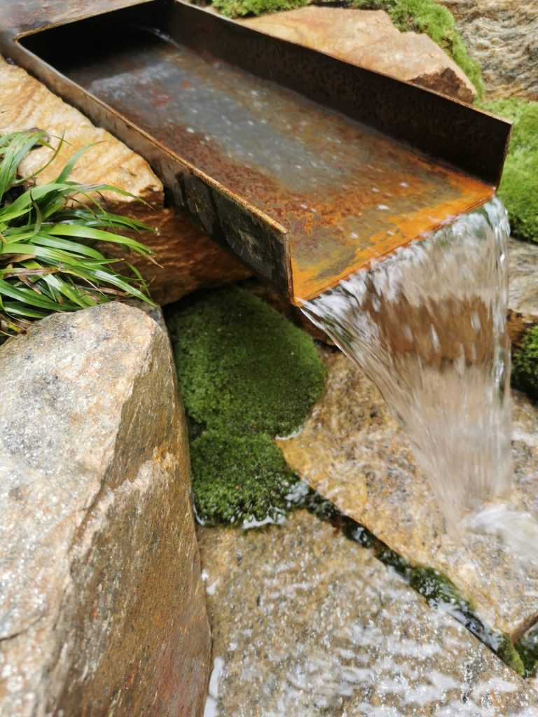 Lame d’eau métallique de la cascade, entourée de mousse à Colombes (92)