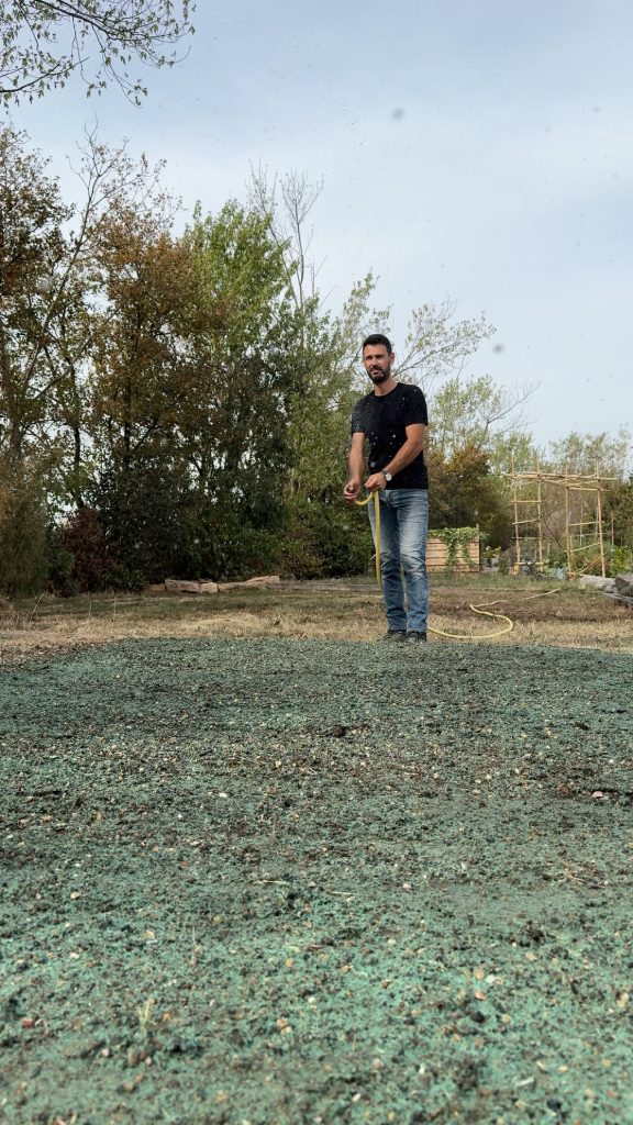 Thomas Bisson humidifie au tuyau un semis hydraulique fraîchement projeté