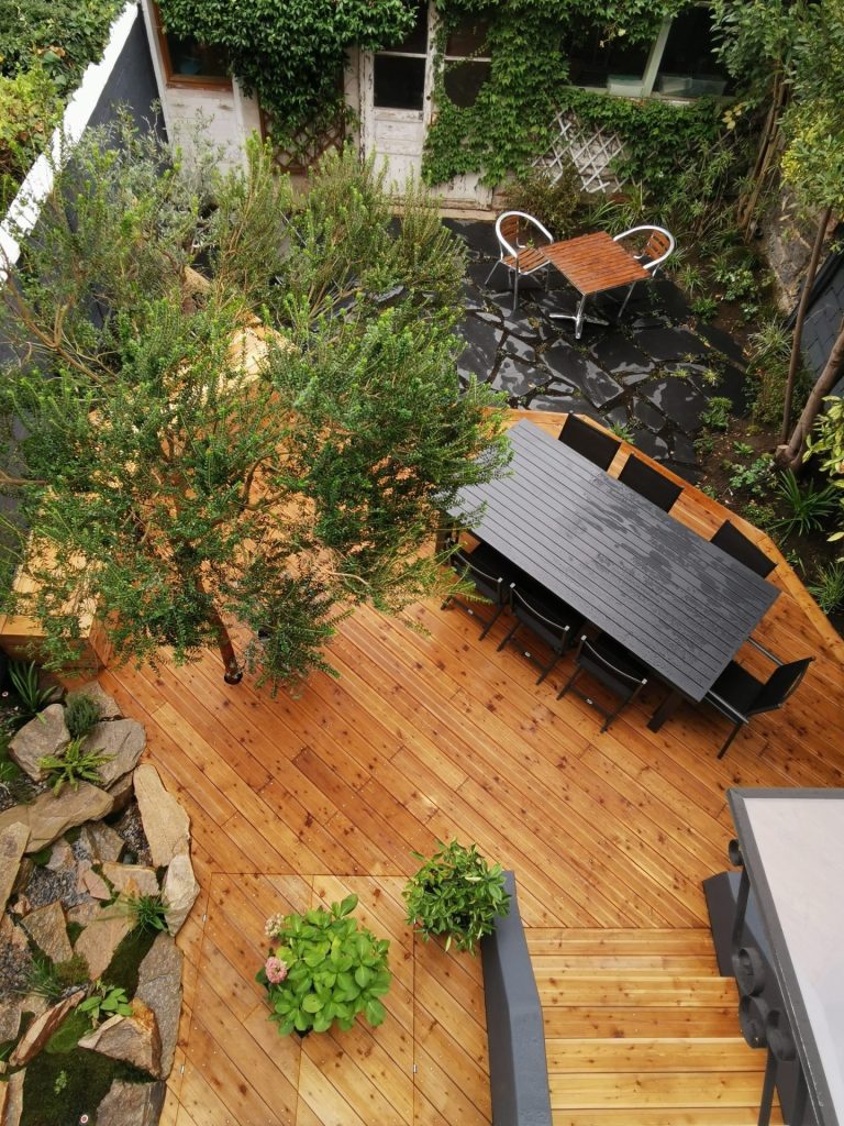 Vue d’ensemble de la terrasse en mélèze terminée, avec son arbre et ses plantations à Colombes (92)
